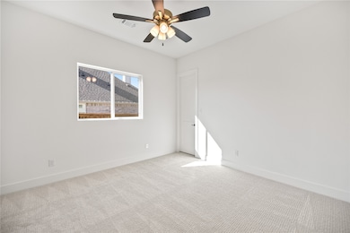 Carpeted spare room with baseboards and a ceiling fan