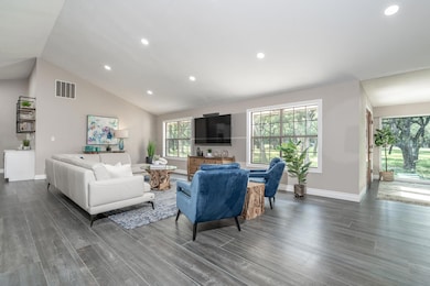 Living room with dark wood-style floors, recessed lighting, and lofted ceiling