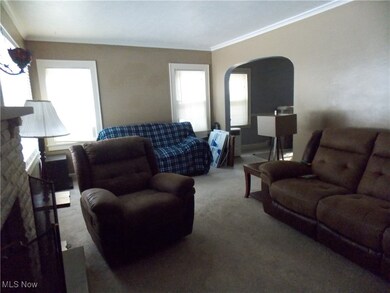 Living room featuring ornamental molding, a stone fireplace, and carpet floors