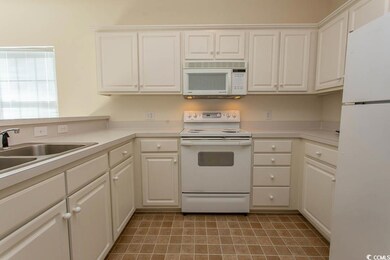 Kitchen with sink, white cabinets, and white appli