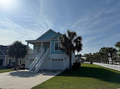 Beach home with stairs, a front yard, concrete dri