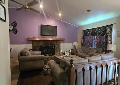 Living area with lofted ceiling, ceiling fan, and a fireplace