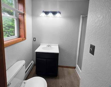 Bathroom with toilet, vanity, a baseboard radiator, and baseboards