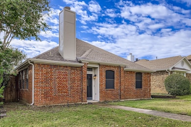 Ranch-style home with a chimney, brick siding, and a shingled roof
