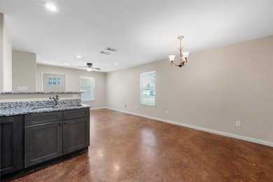 Kitchen featuring light stone countertops, recessed lighting, open floor plan, a chandelier, and a ceiling fan