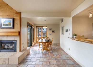 Dining space with a tiled fireplace, stone tile fl