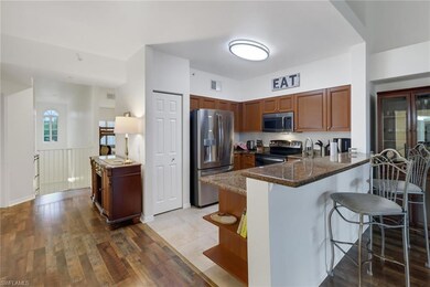 Kitchen with light wood-type flooring, dark stone 