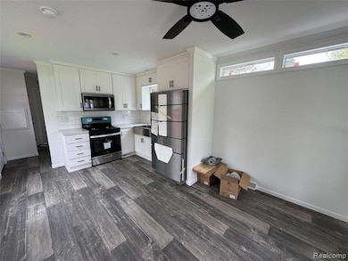 Kitchen with light countertops, stainless steel appliances, white cabinetry, decorative backsplash, and ornamental molding