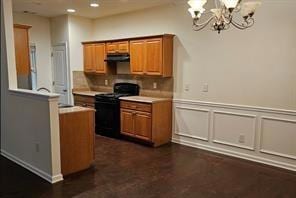 Kitchen with brown cabinetry, a chandelier, black range oven, light countertops, and recessed lighting