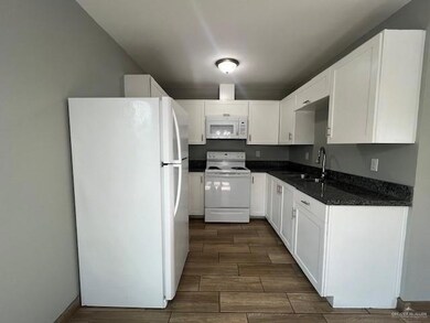 Kitchen with sink, white appliances, white cabinetry, and dark stone counters