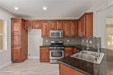 Kitchen with dark stone countertops, light wood fi