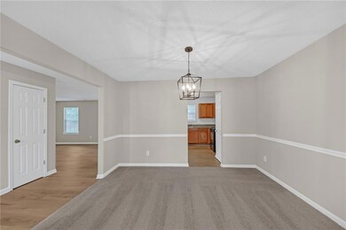 Empty room featuring a chandelier, light carpet, b