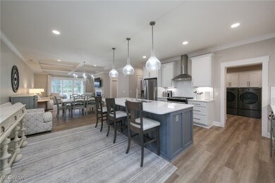 Kitchen with white cabinetry, open floor plan, a kitchen island with sink, a breakfast bar, and decorative light fixtures