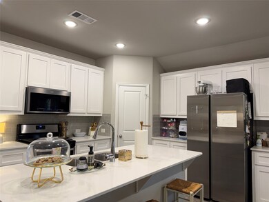 Kitchen featuring white cabinetry, stainless steel appliances, backsplash, a breakfast bar area, and light stone countertops