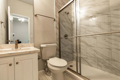 Full bath with a shower stall, vanity, and tile p