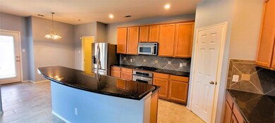 Kitchen with a notable chandelier, backsplash, pendant lighting, a kitchen island, and appliances with stainless steel finishes