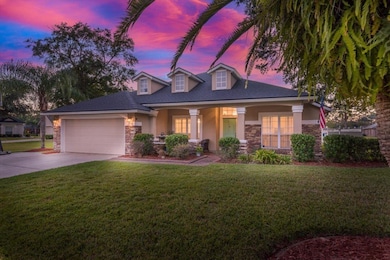 View of front of property with stone siding, a lawn, a porch, and driveway
