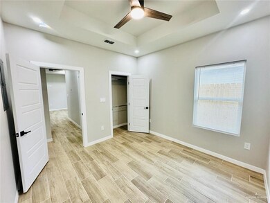 Unfurnished bedroom featuring baseboards, a ceiling fan, visible vents, wood tiled floor, and a raised ceiling