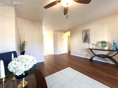 Living room featuring a ceiling fan, baseboards, v