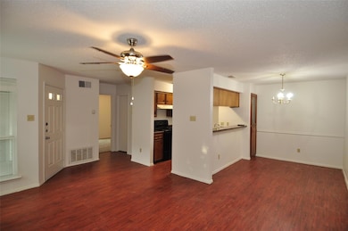 Unfurnished living room featuring dark wood finished floors, a chandelier, ceiling fan, and a textured ceiling