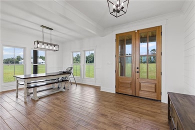 Dining space with crown molding, wood finished floors, a chandelier, and french doors