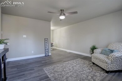 Sitting room featuring ceiling fan and dark hardwo