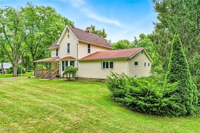 Back of house with a porch, a lawn, roof with shingles, and a chimney