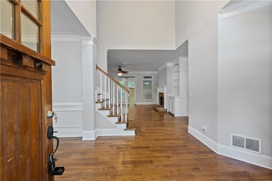 Entrance foyer featuring dark wood-style flooring, decorative columns, a high ceiling, crown molding, and stairs