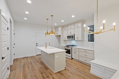 Kitchen featuring GE Cafe appliances tasteful backsplash, light wood finished floors, and decorative light fixtures