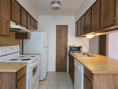 Kitchen with a sink, white appliances, light coun