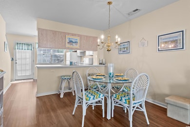 Dining room with wood finished floors, a chandelier, and baseboards