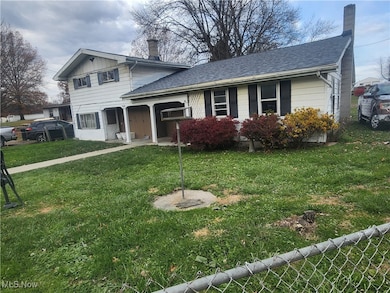 View of front of home featuring a chimney, a front lawn, and covered porch