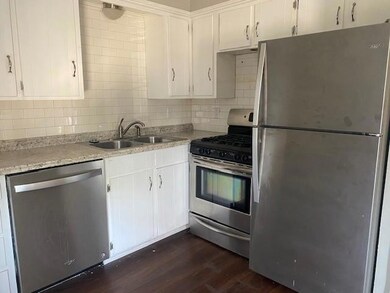 Kitchen featuring appliances with stainless steel finishes, dark wood-type flooring, white cabinetry, and sink