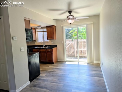 Dining area off of kitchen with dark countertops, a textured wall, a ceiling fan, range, and healthy amount of natural light
