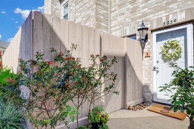 The paved entryway features outdoor lighting, a gl