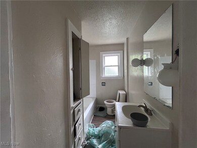 Full bathroom with a textured ceiling, vanity, a textured wall, a bath, and dark wood-style flooring