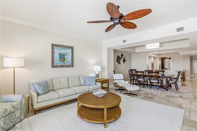 Living room featuring crown molding, a ceiling fan, stone finish floors, and a tray ceiling