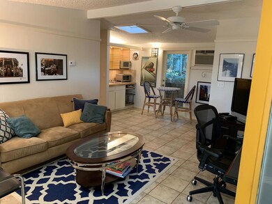 Living area featuring light tile patterned floors, a wall mounted air conditioner, ceiling fan, and a textured ceiling