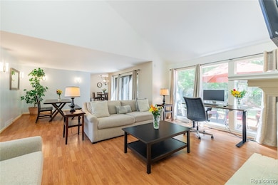 Living room with an office area, high vaulted ceiling, light wood-type flooring, and a chandelier