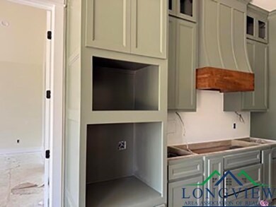 Kitchen featuring wall chimney range hood, gray cabinetry, and glass insert cabinets