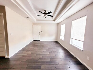 Empty room with a tray ceiling, wood finished floors, and ceiling fan