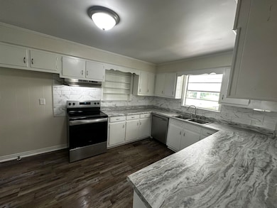 Kitchen with a sink, appliances with stainless steel finishes, crown molding, tasteful backsplash, and light countertops