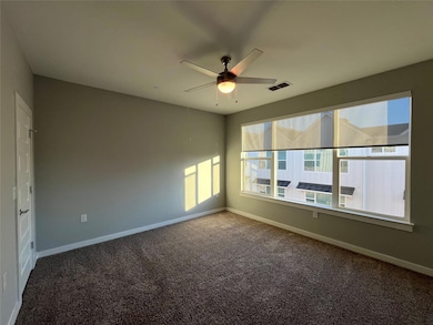 Empty room featuring dark colored carpet and a ceiling fan