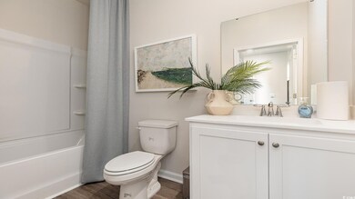 Full bathroom with hardwood / wood-style floors, shower / tub combo with curtain, vanity, and toilet