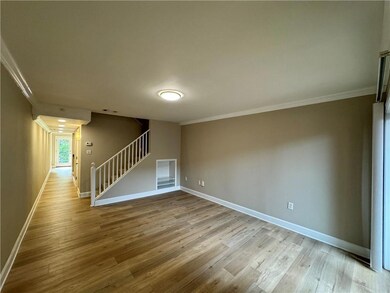 Empty room featuring crown molding, stairs, wood finished floors, and baseboards