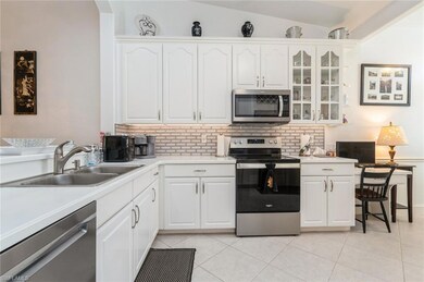 Kitchen featuring appliances with stainless steel finishes, backsplash, light tile patterned flooring, and glass insert cabinets