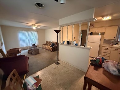 Living room with a ceiling fan and light carpet