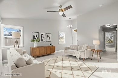 Living area with carpet flooring, healthy amount of natural light, lofted ceiling, arched walkways, and ceiling fan