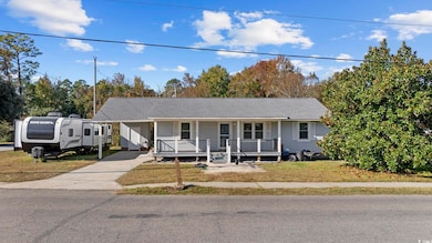 Single story home featuring a porch, roof with shingles, concrete driveway, and a front lawn