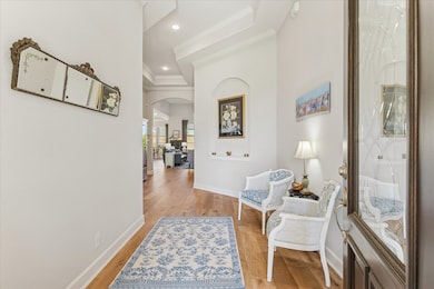 The entryway features LVP flooring, crown molding, and an art niche, leading into a bright, spacious living area.